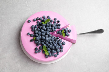 Cut tasty blueberry cake and shovel on light grey table, top view