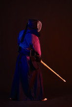 Close Up Shot, Kendo Fighter Wearing In An Armor, Traditional Kimono, Helmet Practicing Martial Art With Shinai Bamboo Sword, Black Background.