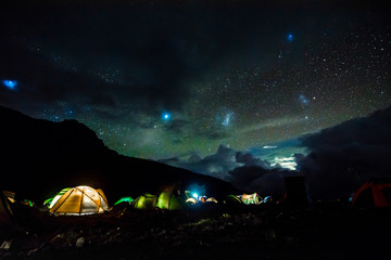 Pitched tents camping at the base of Mount Kilimanjaro at night under the stars