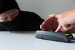 © artursfoto - Thief is stealing pin code and identity on payment (pos) terminal machine. Crime concept