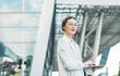 © Petryshak - Close-up of young professional businesswoman using her laptop outside while working at modern business center, modern buildings in the background, flare light.