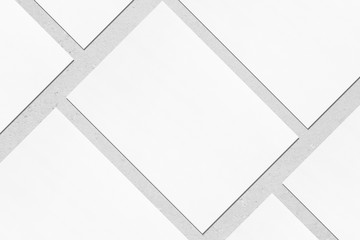 closeup of empty white rectangle poster mockups lying diagonally with soft shadow on neutral light g