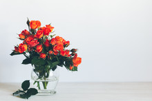 Romantic Bouquet Of Bright Red Orange Roses In A Glass Vase On A White Background.
