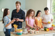 © Pixel-Shot - Happy friends cooking together in kitchen