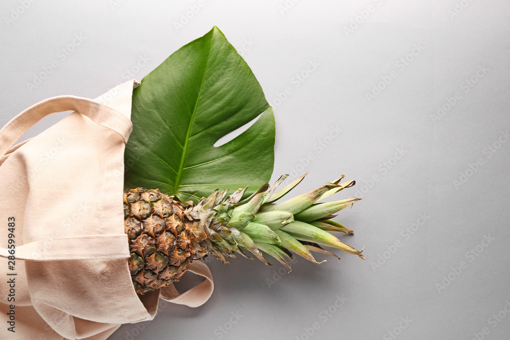 Eco bag with pineapple and tropical leaf on grey background