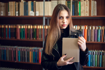 Beautiful teenager schoolgirl reading a book in the library