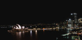 Fototapeta Nowy Jork - Aerial wide angle panorama of the city of Sydney overlooking the Sydney Opera House at night, with all the buildings illuminated. View from the Harbor Bridge.