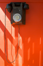 Antique Black Telephone In Red Wall With Sunshade Background.