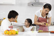 © xreflex - Happy Asian family make a cooking. Father, Mother and Daughter are preparing fruit, green apple in the kitchen at home. Healthy food concept and happy holidays