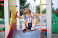 A Little Girl Riding A Slide On The Playground.kid Playing In Kindergarten In The Summer