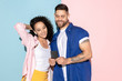 © master1305 - Young emotional caucasian couple in bright clothes posing on pink and blue background. Concept of human emotions, facial expession, relations, ad. Man and woman make selfie in wireless earphones.