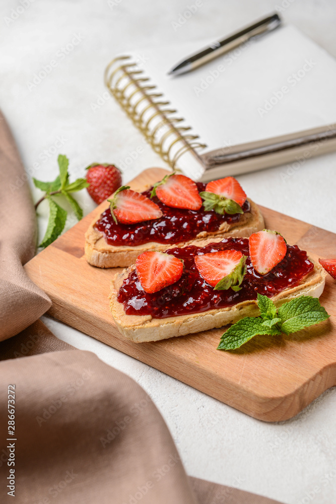 Wooden board with toasted bread and strawberry jam on white table