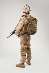 Soldier in US marines uniform with rifle on light grey background, studio shot