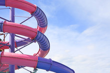 Detail Of Serpentines Of The Tubes Of A Water Slide Of Swimming Pool Against Sky Background.