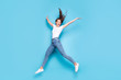 © deagreez - Full size photo of pretty teen raising hands screaming laughing wearing white t-shirt denim jeans sneakers isolated over blue background