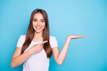 Canvas Print - Portrait of lovely millennial holding hand pointing to ads with her index finger isolated over blue background