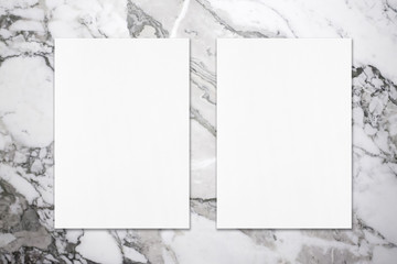 Two empty white vertical rectangle poster mockups with soft shadows on grey marble background. Flat lay, top view