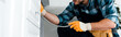 © LIGHTFIELD STUDIOS - panoramic shot of repairman holding metal hose near kitchen cabinet