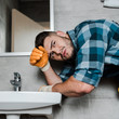 © LIGHTFIELD STUDIOS - handsome bearded handyman standing near sink in bathroom