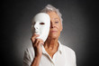 © Axel Bueckert - serious looking older woman revealing true face behind mask