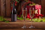 Fototapeta Lawenda - Christmas holiday table with glasses and a bottle of wine of champagne. Eve of new year, preparation and laying of a wooden holiday table
