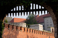 View Through The Arched Gate Of The Castle On The Wall Of The Old Town On A Sunny Summer Day. Wooden Fence To Close Access To Private Areas