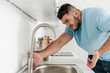 © LIGHTFIELD STUDIOS - angry man gesturing near faucet in kitchen
