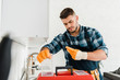 © LIGHTFIELD STUDIOS - selective focus of handsome handyman looking at toolbox in kitchen