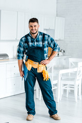 Wall Mural - happy bearded workman standing with hand on hip and holding clipboard