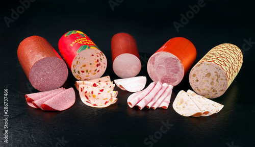 Fotomural Traditionelle deutsche Aufschnitt Wurst als closeup vor schwarzen Hintergrund mi