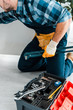 © LIGHTFIELD STUDIOS - cropped view of handyman working near kitchen cabinet and toolbox with instruments
