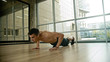 © KONSTANTIN SHISHKIN - An athletic shirtless man training in the studio - doing push ups