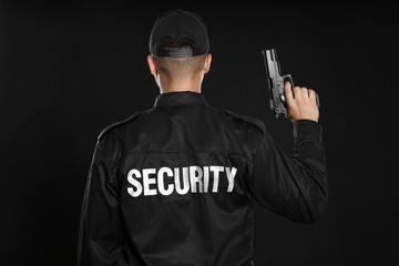 Male security guard in uniform with gun on dark background