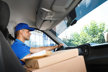 Poster - Young courier with parcels in delivery car