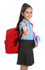 Poster - Cute little girl in school uniform with backpack and stationery showing thumbs-up on white background