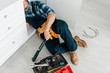 © LIGHTFIELD STUDIOS - cropped view of bearded repairman working near kitchen cabinet and toolbox
