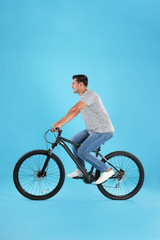 Poster - Handsome young man with modern bicycle on light blue background