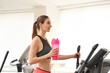 © New Africa - Athletic young woman with protein shake on running machine in gym