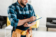 © LIGHTFIELD STUDIOS - cropped view of bearded worker writing while holding clipboard