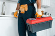 © LIGHTFIELD STUDIOS - cropped view of worker in uniform standing and holding toolbox