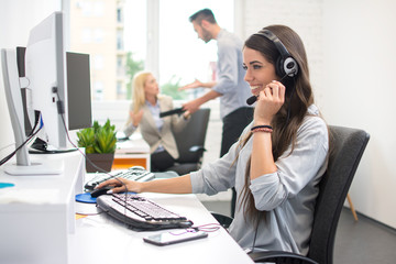 Beautiful female dispatcher with hands-free headset helping a client via online video or audio call.