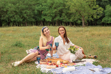 Two young friends enjoy outdoor picnic on green lawn.