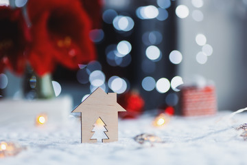 Wooden icon of house with hole in form of fir with red home Christmas decor and blurred bokeh background in daylight.