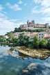 The old town of Béziers reflected in the waters of Orb river in a summer day. Béziers, France.