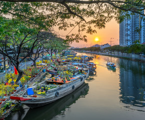 Wall Mural - Ho Chi Minh City, Vietnam - February 3rd, 2019: Sunset boat dock flower market along canal wharf. This is place farmers sell apricot and other flowers on Lunar New Year in Ho Chi Minh city, Vietnam