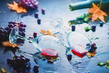 tall wine glasses with grapes and fallen leaves under rain. creative autumn drink photography with c