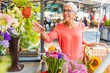 © Dragana Gordic - Portrait of a beautiful senior woman doing shopping in a market on a sunny morning, she carries a basket with fruits and vegetables and a bouquet of flowers. Woman buying flowers on the local market..