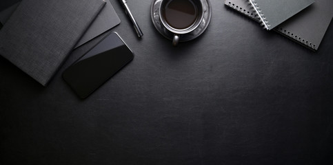 Wall Mural - Dark trendy workplace with smartphone and office supplies on black leather table background
