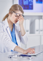 Wall Mural - Young female doctor tired after working with computer