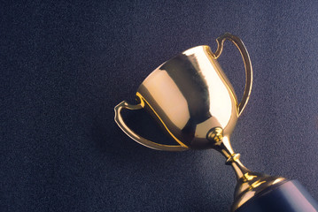 Wall Mural - gold shinny trophy lay on black background.